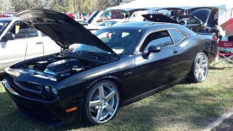 2007 Ford Mustang - A black Dodge Challenger is parked on grass with its hood open, revealing the engine compartment.