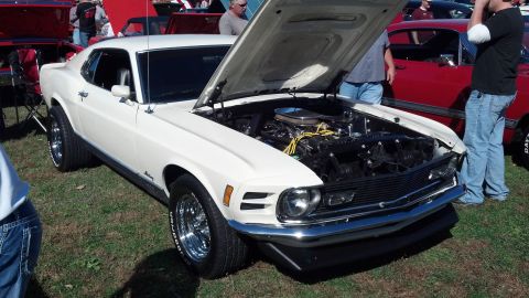 2007 Ford Mustang - A white 1970 Ford Mustang coupe is displayed with its hood open, revealing the engine bay. The car features chrome wheels and is parked on…