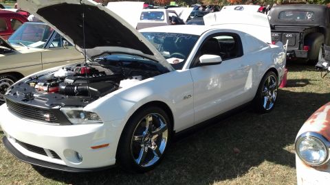 2007 Ford Mustang - A white Ford Mustang is displayed with its hood open at an outdoor car show.