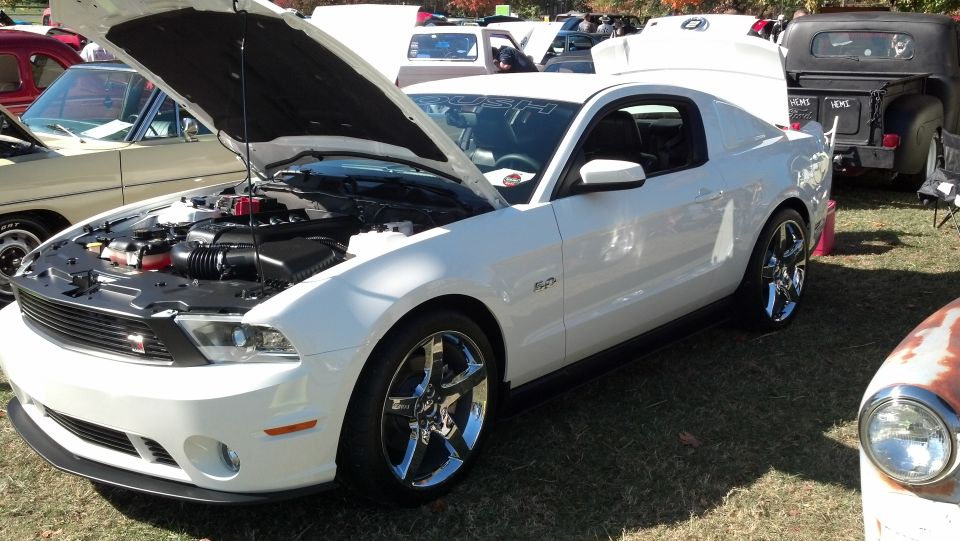 White Ford Mustang with hood open, chrome wheels, and a 5.0 badge on the fender