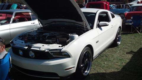 2007 Ford Mustang - A white Ford Mustang from the 2010-2014 generation is displayed with its hood up, parked on grass next to other vehicles.