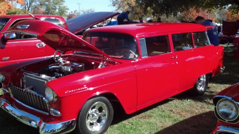 2007 Ford Mustang - A bright red vintage station wagon is displayed with its hood up at an outdoor car show.