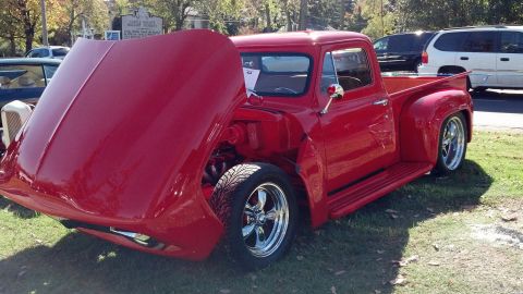 2007 Ford Mustang - A bright red pickup truck from the 1950s is displayed with its hood open, revealing the engine compartment and custom wheels.
