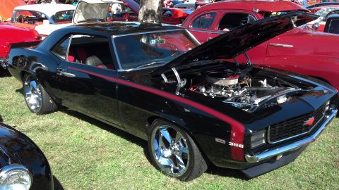 2007 Ford Mustang - A black 1969 Chevrolet Camaro with red racing stripes and chrome wheels is displayed with its hood open.