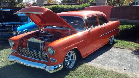 2007 Ford Mustang - An orange 1955 sedan is displayed with its hood and trunk open, parked next to a blue vehicle.