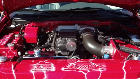 2007 Ford Mustang - Customized engine bay features a supercharger and lightning bolt graphics on red painted surfaces.