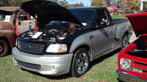 2007 Ford Mustang - Two-tone black and silver Ford F-150 Lightning pickup truck with hood open at a car show.