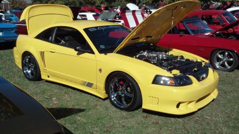 2007 Ford Mustang - Yellow Saleen Mustang at a car show, hood and trunk open, revealing the engine.