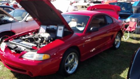 2007 Ford Mustang - A red Ford Mustang is displayed with its hood and trunk open at an outdoor car show.