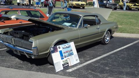 2007 Ford Mustang - A classic Mercury Cougar is displayed with its hood open at an outdoor car show.