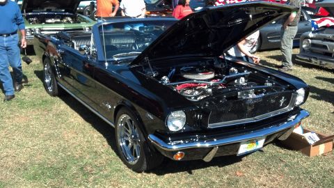 2007 Ford Mustang - Black classic convertible Mustang with hood open at a car show, other vehicles visible.