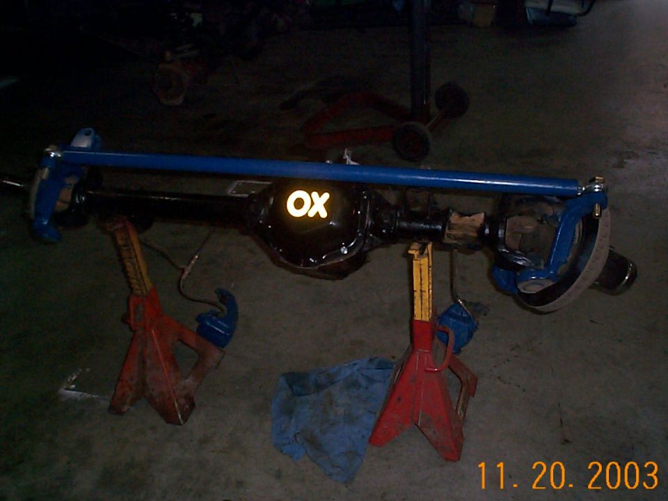 Rebuilt front solid axle on jack stands, black housing with blue knuckles and OX diff cover decal
