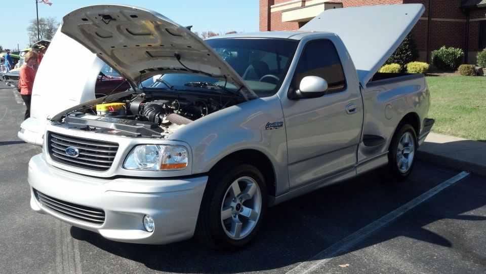 Silver Ford F-150 Lightning pickup truck with hood and bed open, showing engine