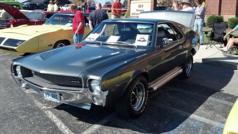 2007 Ford Mustang - A classic gray AMC AMX is displayed at an outdoor car show with other vehicles present.