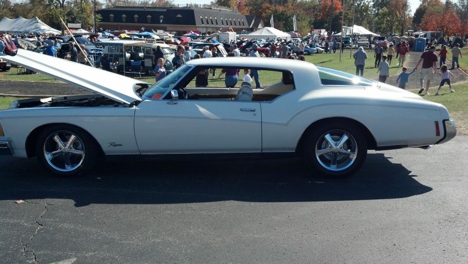 White coupe with hood open, chrome wheels, tan interior, side view