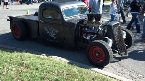2007 Ford Mustang - A heavily modified black pickup truck with a prominent engine and custom "Ripper" artwork on the door is displayed at an outdoor event.