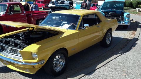 2007 Ford Mustang - Yellow 1967 Ford Mustang coupe at a car show, hood open, with other cars visible.