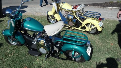2007 Ford Mustang - Two vintage mini bikes are parked on grass, one teal and one yellow.