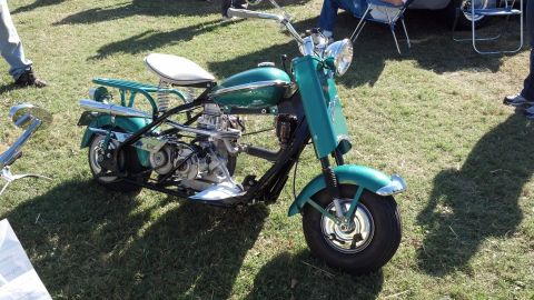 2007 Ford Mustang - A vintage scooter with a distinctive green body and white seat is displayed outdoors on a grassy area.