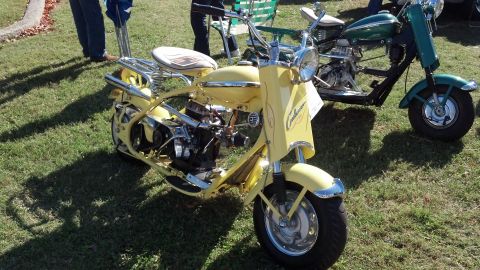 2007 Ford Mustang - A yellow scooter is parked on a grassy lawn next to a green scooter.