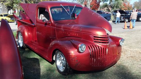 2007 Ford Mustang - A shiny red pickup truck is displayed with its hood and bed cover open, revealing custom paintwork and chrome wheels.