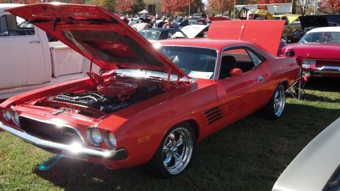 2007 Ford Mustang - A classic red Dodge Challenger is displayed with its hood open at an outdoor car show event.