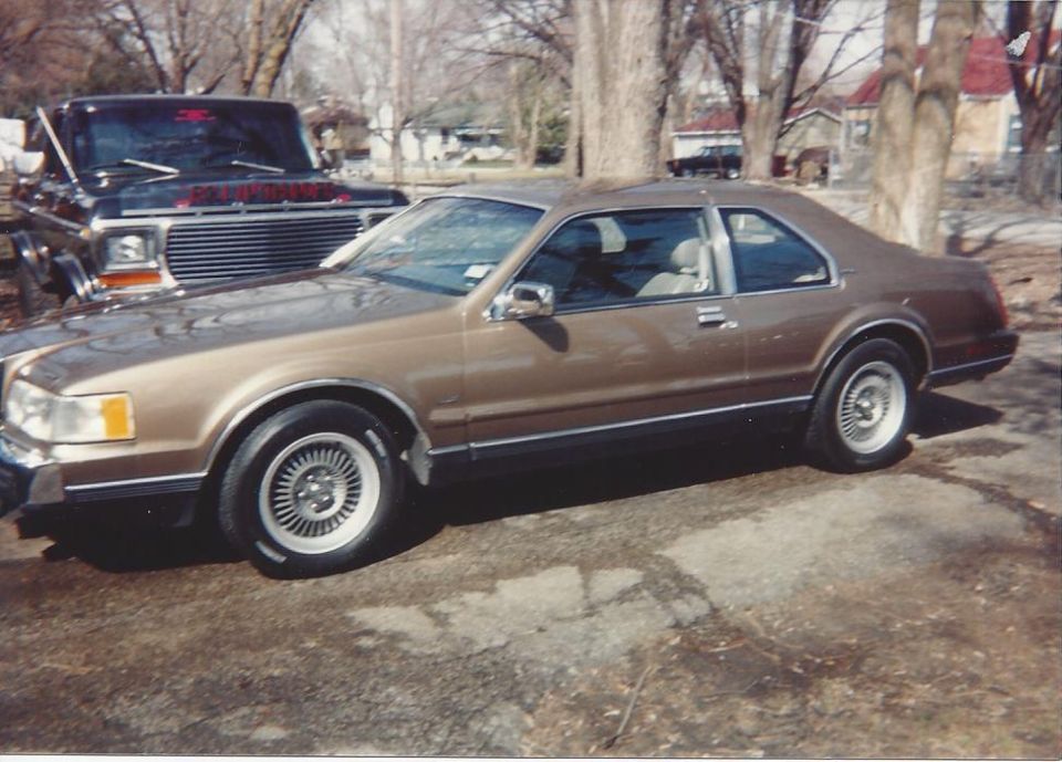 Brown coupe parked next to a black pickup truck