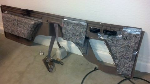 1995 Ford Bronco - A disassembled brown door panel with insulation material and a seatbelt mechanism is shown.