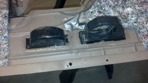 1995 Ford Bronco - Two black plastic mounting brackets are secured to a gray interior panel, with insulation visible on the side.