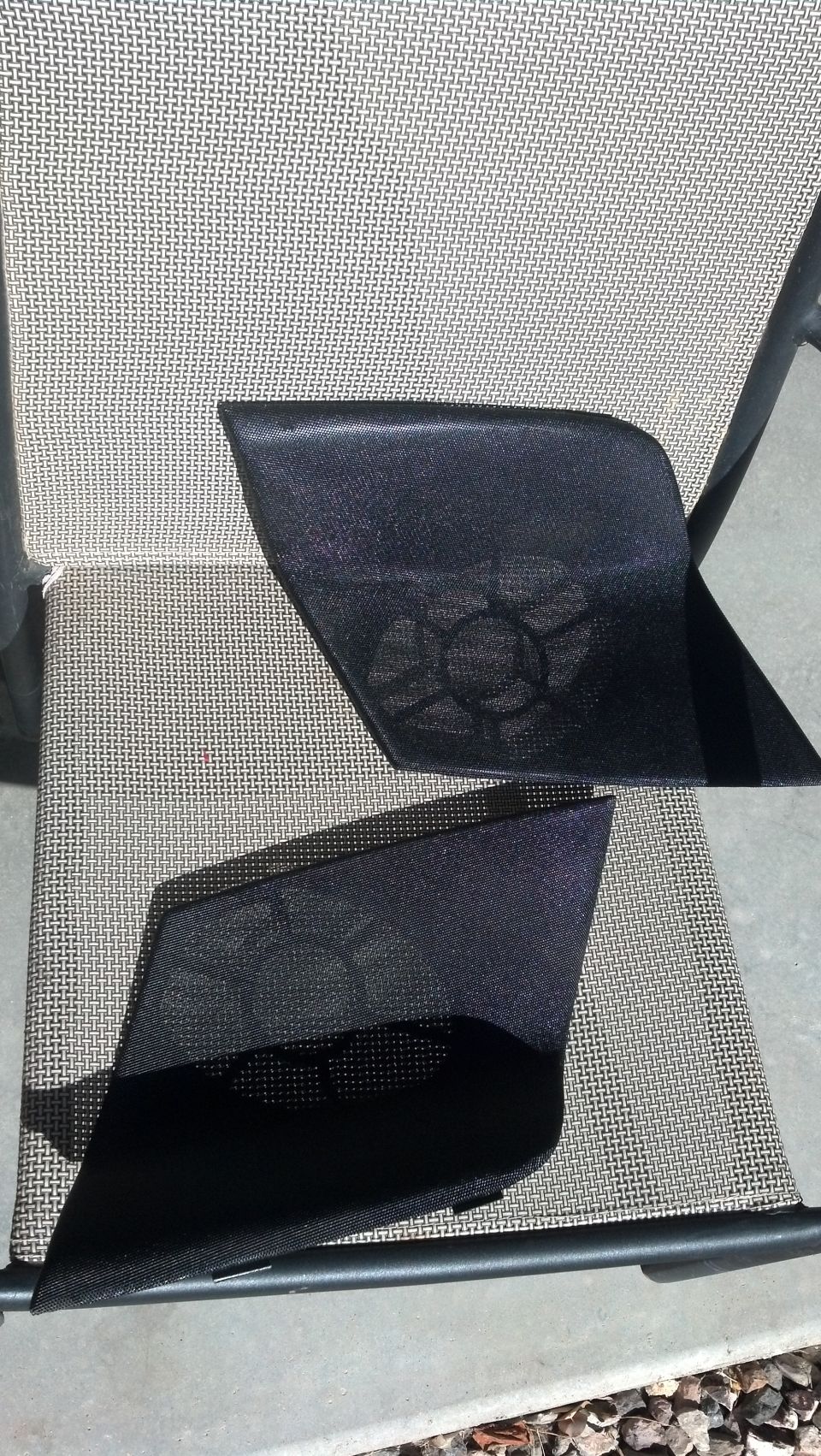 Two black car door speaker grilles with mesh pattern, resting on a chair