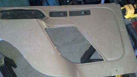 1995 Ford Bronco - A tan interior door panel is shown, two buttons and a large opening for a speaker or storage.