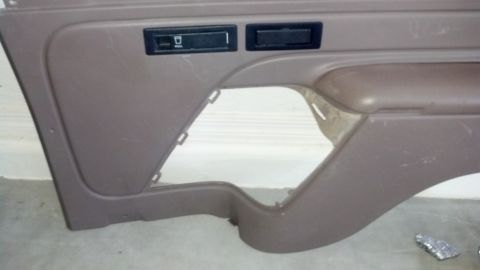 1995 Ford Bronco - A brown car door panel is shown, two black slots and a large cutout area.