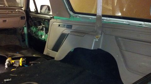1995 Ford Bronco - Disassembled interior of a 1995 Ford Bronco, showing exposed green body panels and a drill on the carpet.