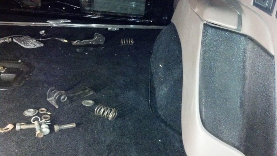 Interior of a vehicle with carpeted floor, disassembled metal parts, and springs scattered around