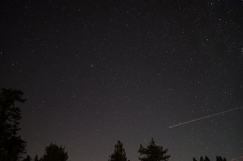 2003 Ford Taurus - A clear night sky filled with stars is visible above a silhouetted treeline, with a distant airplane contrail streaking across the frame.
