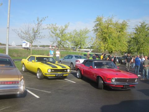 1991 Ford LTD Crown Victoria - Two classic American muscle cars, a yellow Camaro and a red Mustang convertible, are parked side-by-side.