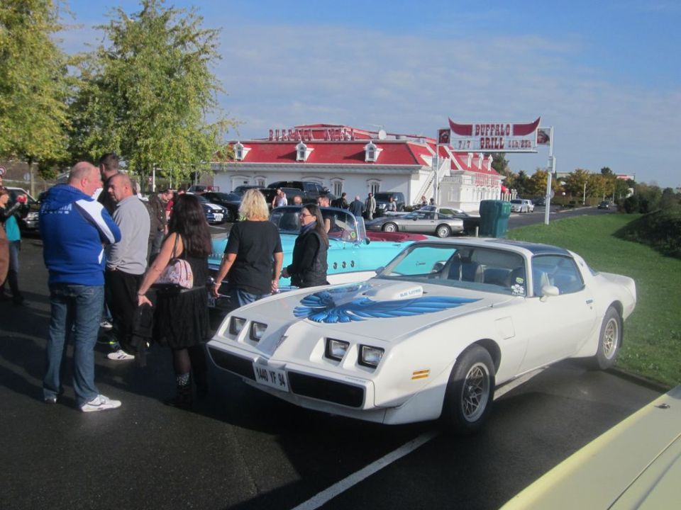 White Pontiac Firebird Trans Am with blue hood decal parked outside Buffalo Grill