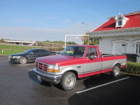 1991 Ford LTD Crown Victoria - 1992 Ford F-150 pickup truck parked in a lot with a black sedan.