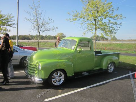 1991 Ford LTD Crown Victoria - A vintage lime green pickup truck with flame decals is parked next to a silver sedan.