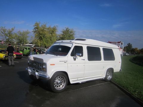 1991 Ford LTD Crown Victoria - A white conversion van is parked at an outdoor event with other vehicles visible in the background.