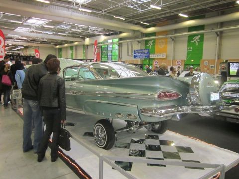 1991 Ford LTD Crown Victoria - A light blue 1959 Chevrolet Impala is displayed at a car show with people admiring it.