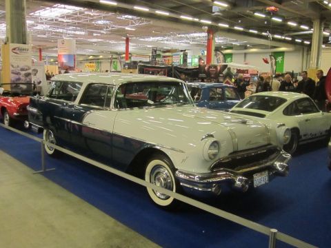 1991 Ford LTD Crown Victoria - A classic two-tone station wagon is displayed at an indoor event with other vehicles.