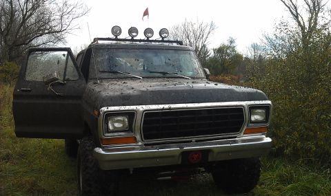 1979 Ford Bronco - This muddy 1979 Ford Bronco sits in a field with its door ajar, ready for its next off-road adventure.