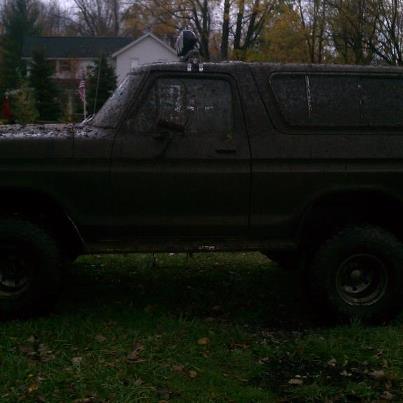 1979 Ford Bronco - This mud-covered SUV, likely from the late 1970s, is seen from the side with a light bar on its roof.