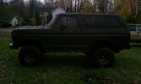 1979 Ford Bronco - Mud-covered 1978 Ford Bronco parked on grass with another vehicle in the background.
