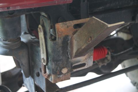 1990 Ford Bronco - Close-up view of a rusted metal bracket and red bellows on the undercarriage of a vehicle.