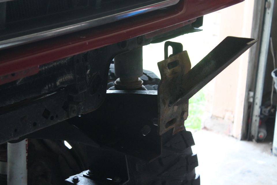 Aftermarket bumper bracket attached to vehicle frame, showing suspension and tire