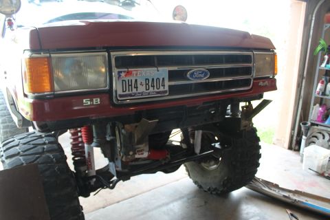 1990 Ford Bronco - This Ford F-Series truck features a lifted suspension and oversized tires, with a Texas license plate on the front grille.