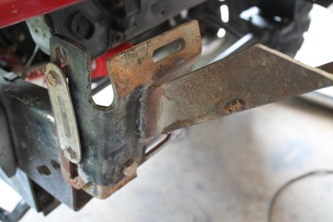 1990 Ford Bronco - Close-up of a corroded metal bracket on a vehicle's undercarriage.
