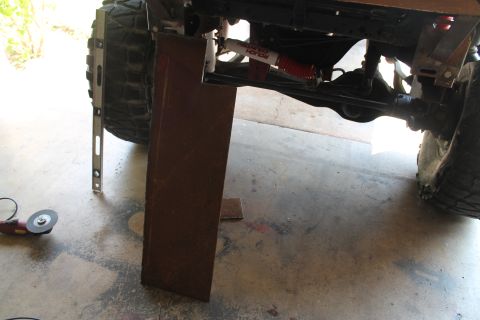 1990 Ford Bronco - Close-up of a vehicle's undercarriage, showing suspension components and a large tire, with tools nearby.